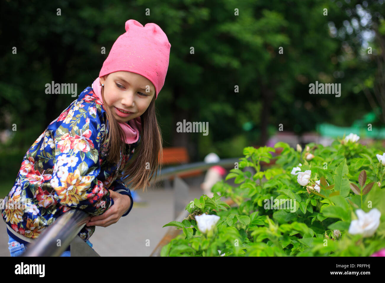 Bel enfant fille avec de longs cheveux en rose cap smiling outdoors. Banque D'Images