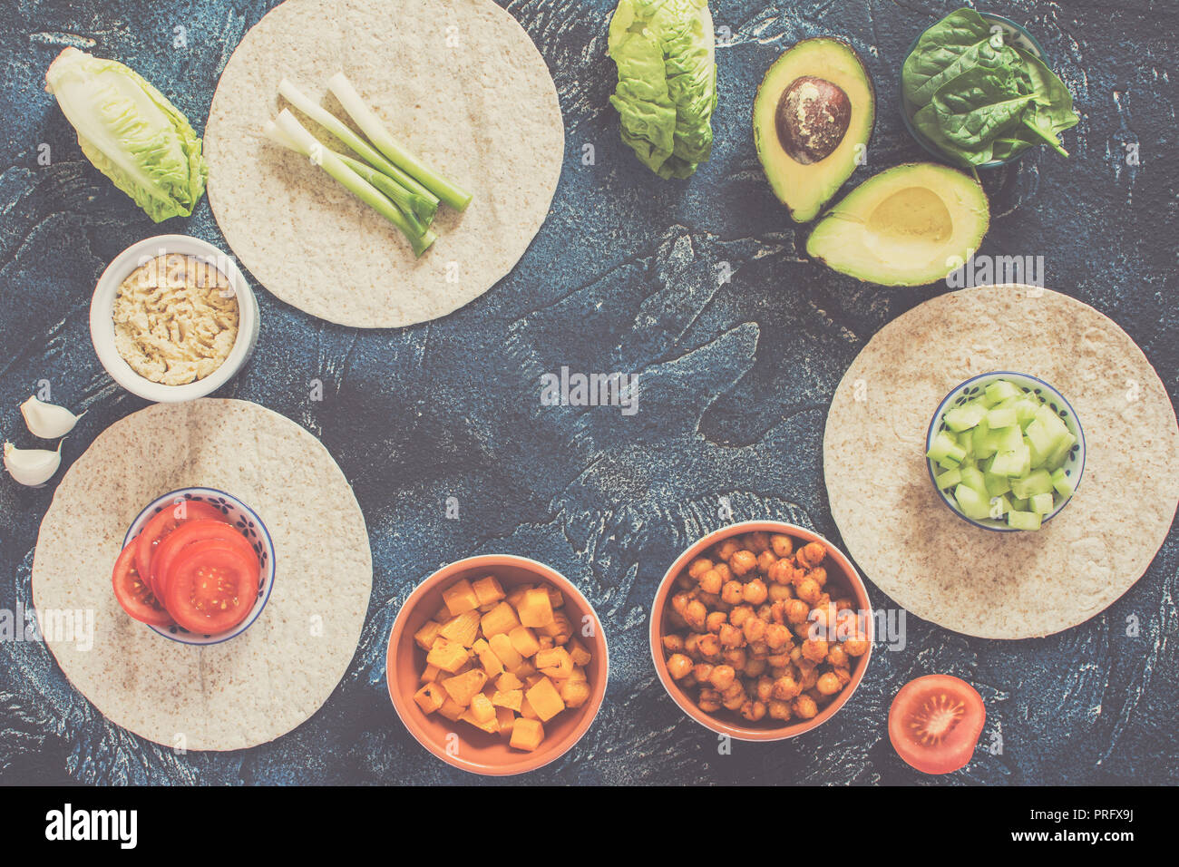 Ingrédients pour les tortillas vegan, pois chiches, oignons, courge, concombre, d'avocat sur le bleu foncé, vue de dessus de table Banque D'Images