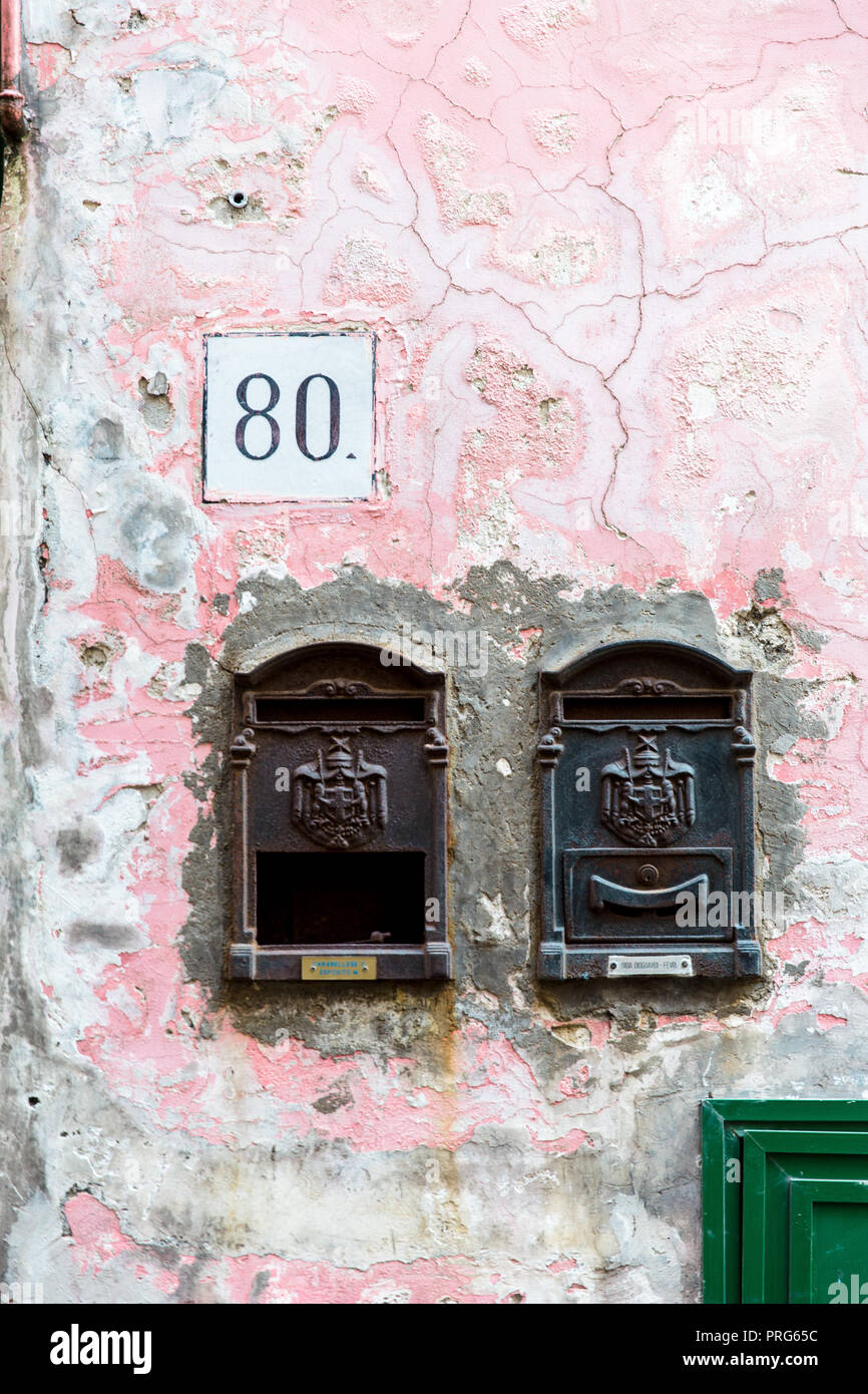 Les boîtes de courrier électronique et un numéro de maison '80' nom sur un mur rose en ruine sur l'île de Procida à Naples, Italie Banque D'Images