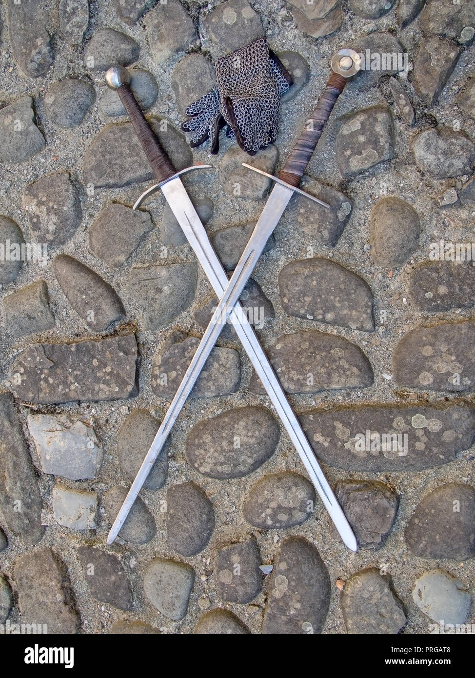 Deux épées médiévales, croisés, sur les pavés, avec des gants en mailles. Banque D'Images