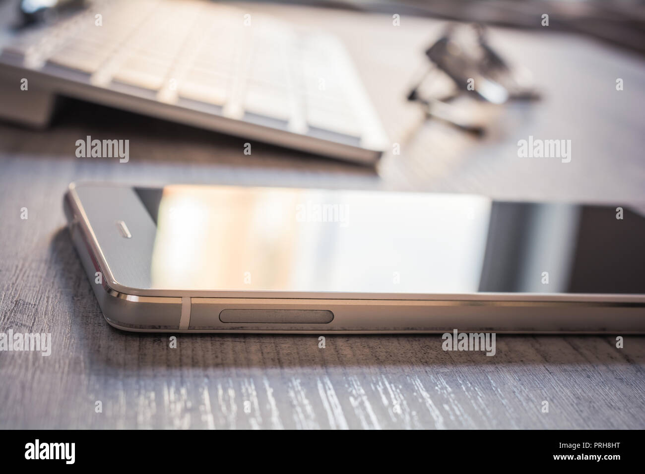 Smartphone avec la réflexion, une paire de lunettes et d'un clavier blanc sur une table - Bureau Concept de poste de travail Banque D'Images