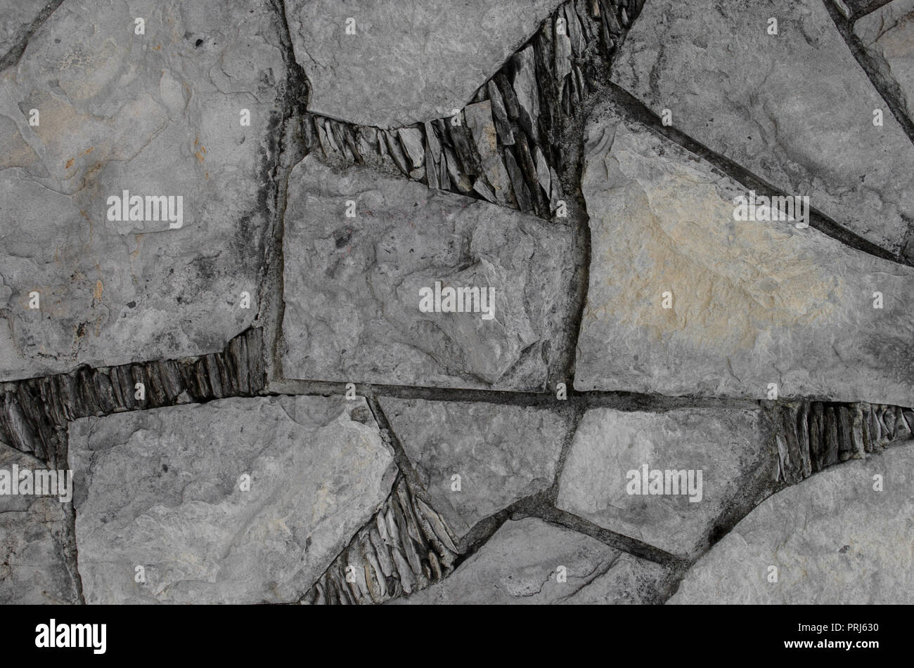 Mur avec des morceaux de pierres en formes géométriques, l'arrière-plan décoratif naturel. Banque D'Images