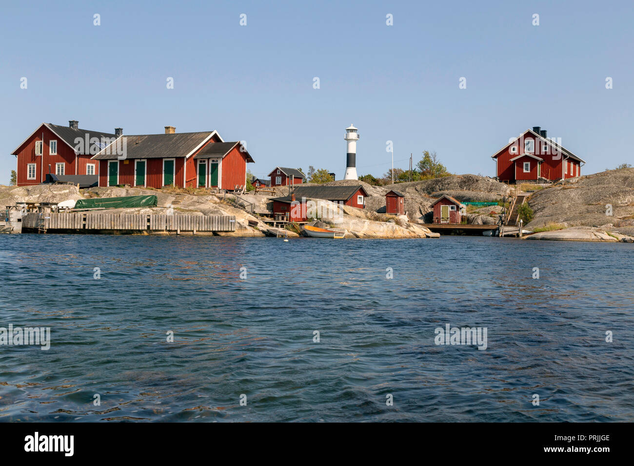 Maisons en bois rouge avec le phare sur la côte rocheuse, l'archipel de Stockholm, la Suède, l'île de l'archipel Huvudskär Banque D'Images