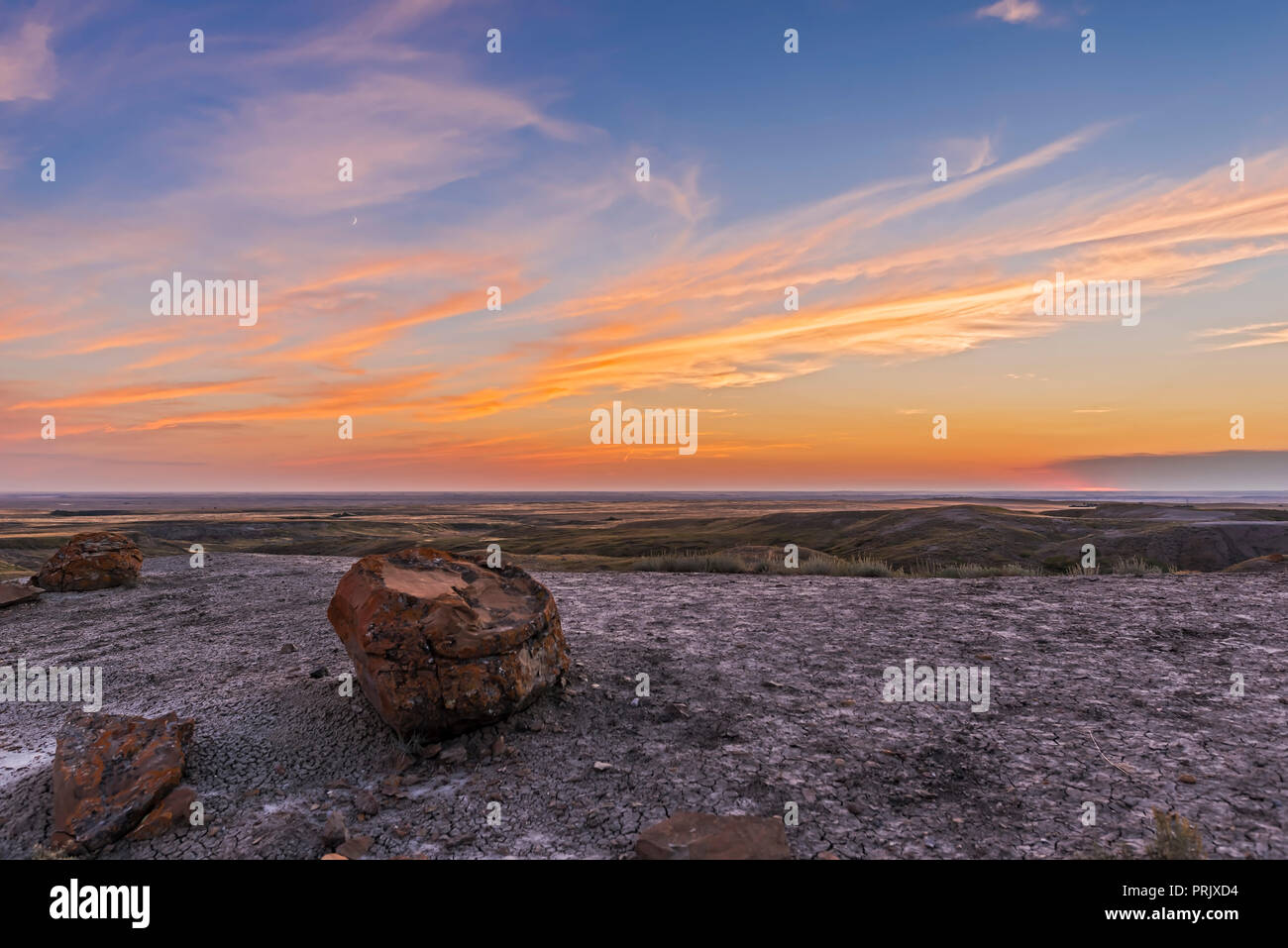 L'épilation à 3 jours croissant de lune dans le ciel du soir sur le Red Rock Coulee zone naturelle dans le sud-est de l'Alberta. Le soleil a mis au point sur l'hori Banque D'Images