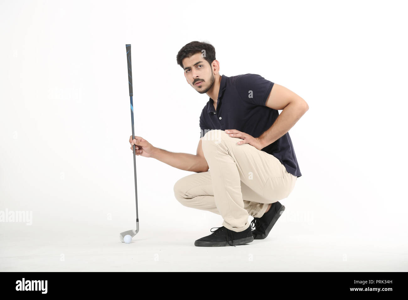 Photo de jeune garçon assis avec bâton de golf et une balle de golf. Isolé sur fond blanc. Banque D'Images