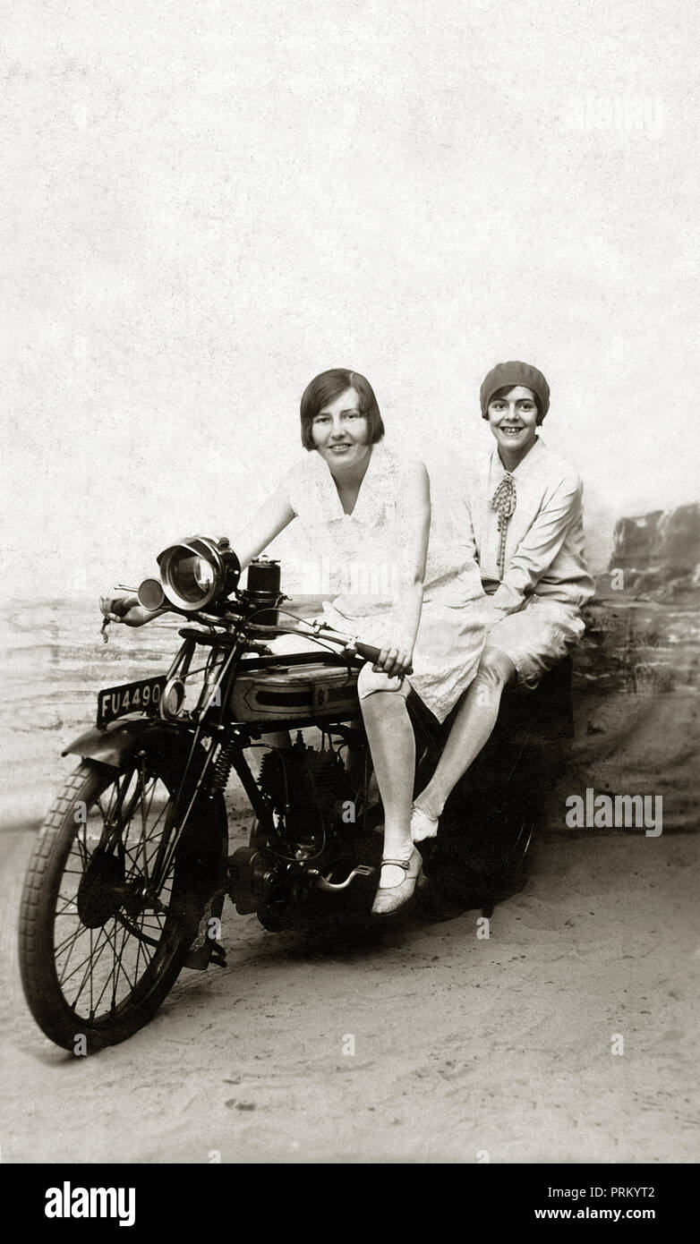 Deux jeunes filles posent pour une photographie contre une station sur une  toile de 1922 Triumph moto SD dans les années 1920 Photo Stock - Alamy