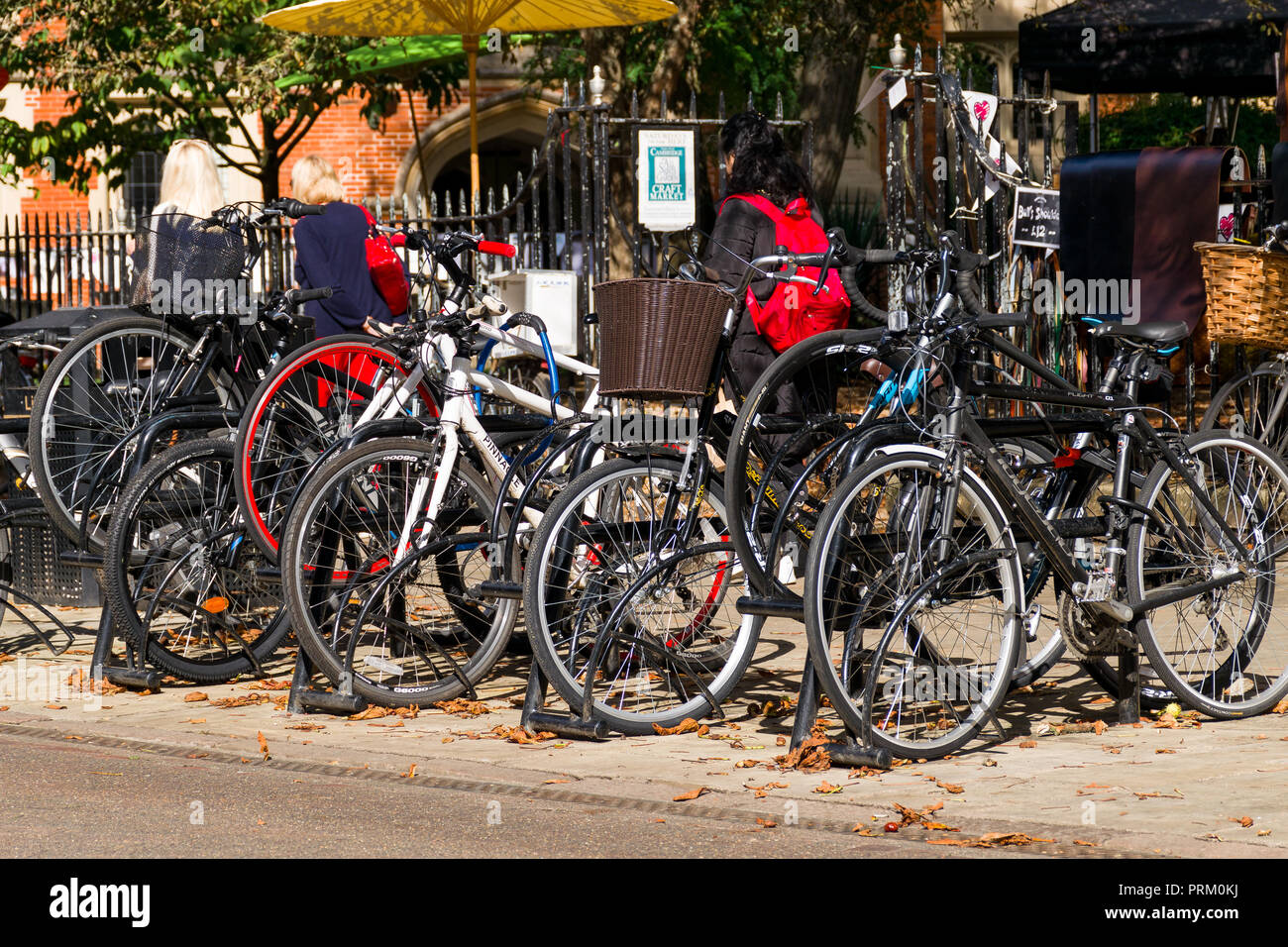 Une rangée de vélos garés sur Trinity Street avec les personnes qui s'y passé sur une journée ensoleillée, Cambridge, Royaume-Uni Banque D'Images