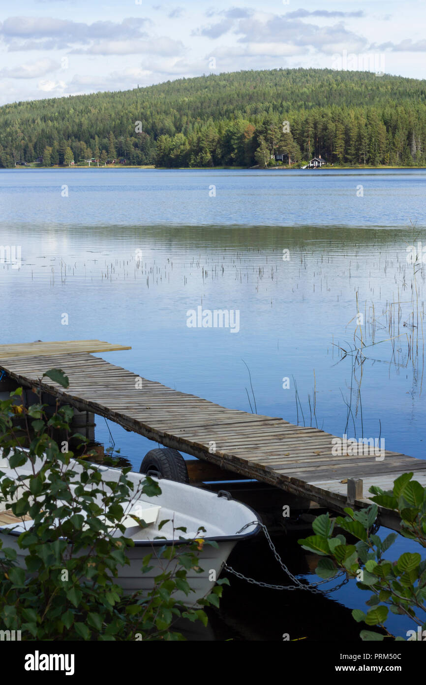 Lac de la forêt avec des chalets. Bateau amarré à quai dans l'avant-plan. Banque D'Images