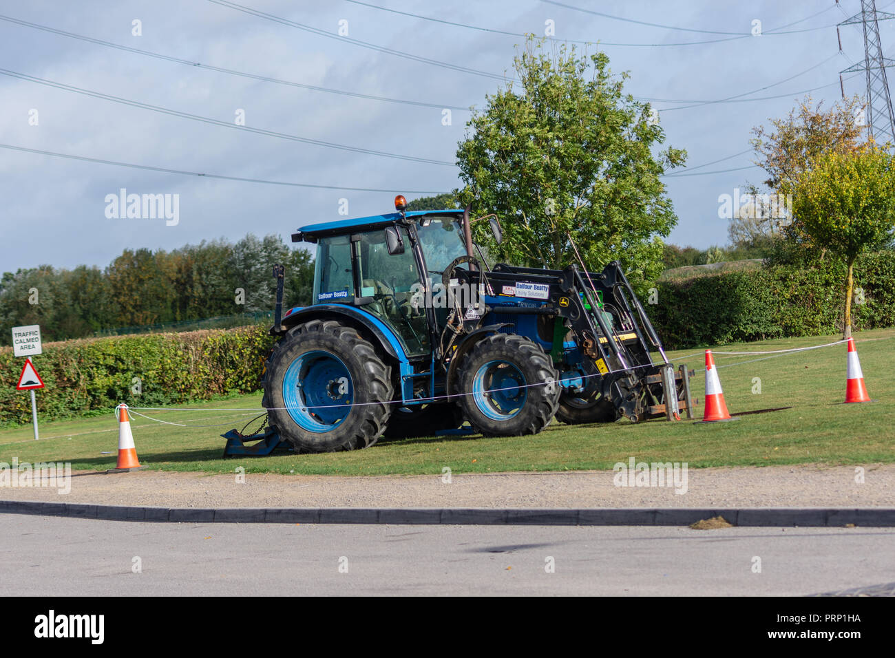 Bleu un tracteur John Deere avec Balfour Beatty autocollants garé sur l'herbe dans une zone encerclée avec corde et cônes Banque D'Images