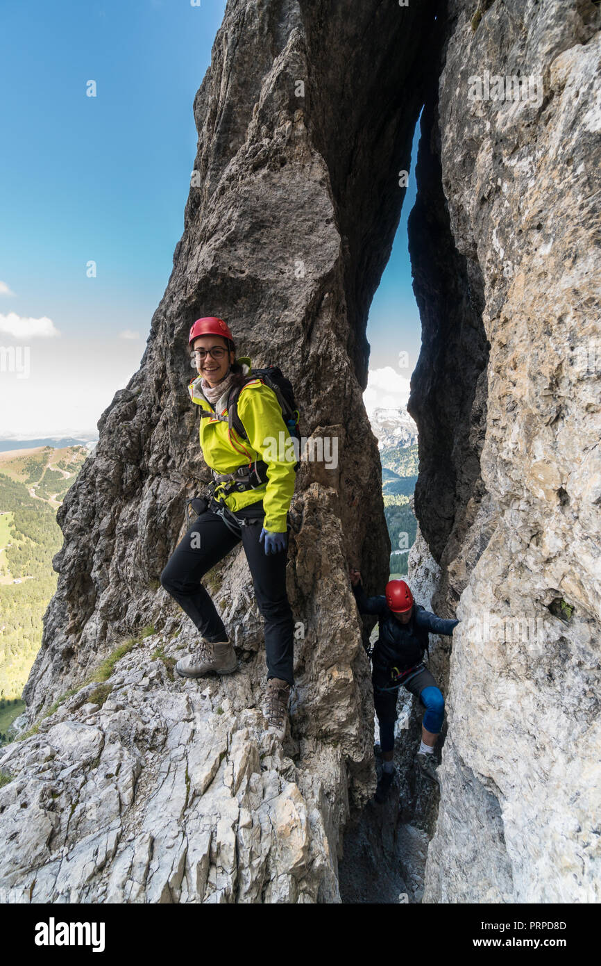Deux jeunes femmes d'alpinistes passer par une étroite fissure sur une montée raide dans les Dolomites d'Alta Badia en Italie du nord Banque D'Images