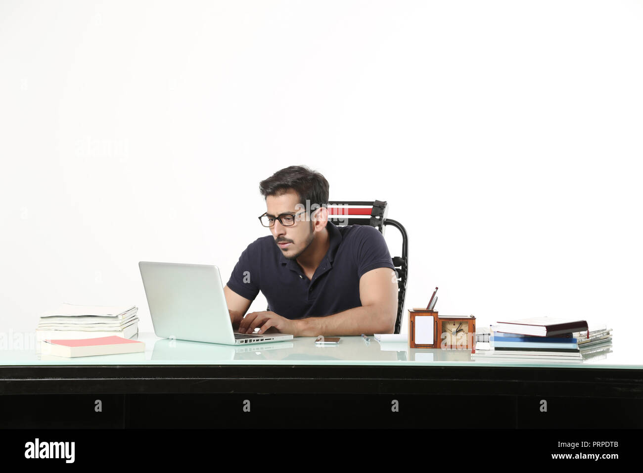 L'homme d'affaires travaille sur un ordinateur portable avec le port de lunettes noires dans la cabine. Isolé sur fond blanc. Banque D'Images