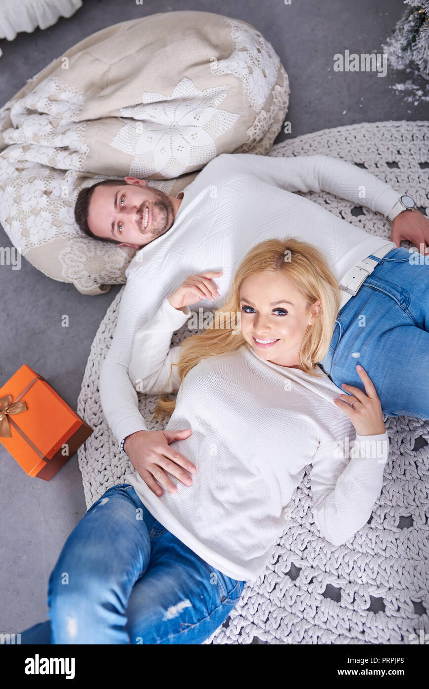 Un beau couple allongé sur le sol avec l'arbre de Noël et les cadeaux. Banque D'Images