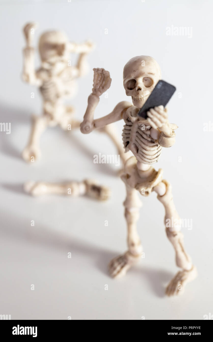 Chiffres squelette avec jambe cassée tout en tenant un téléphone avec selfies Banque D'Images