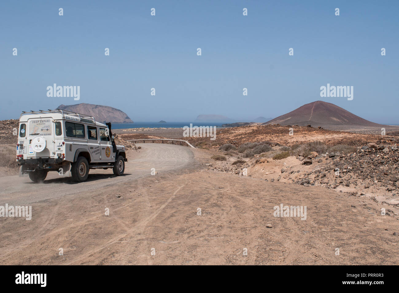 Lanzarote, Canaries : un 4x4 sur le chemin de terre à Playa de las Conchas beach et le volcan montagne Montana Bermeja (Scarlet) de La Graciosa Banque D'Images