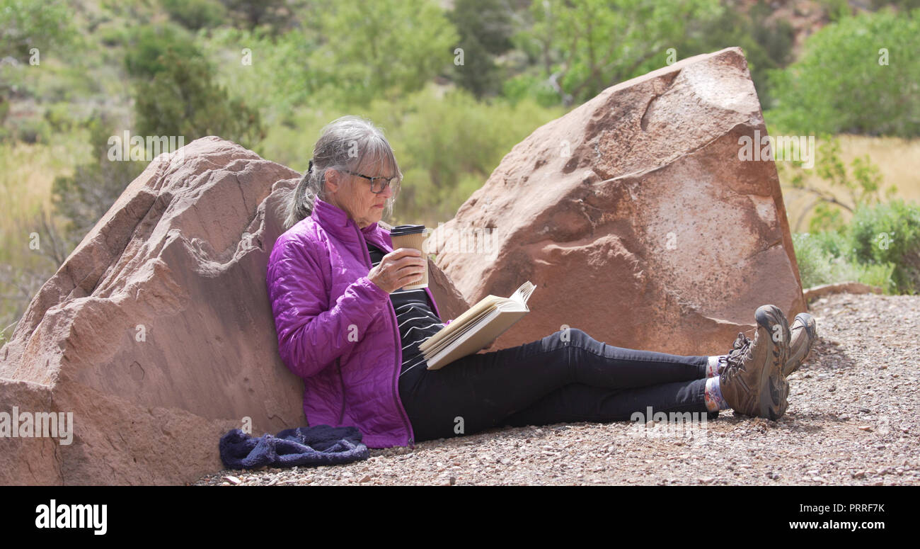 Les amateurs de plein air détendue de boire du café et de la lecture livre dans le canyon de grès Banque D'Images