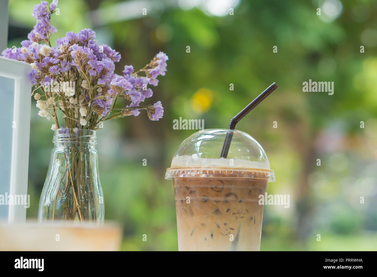 Café de glace dans du plastique transparent avec des fleurs sèches sur table cafe Banque D'Images