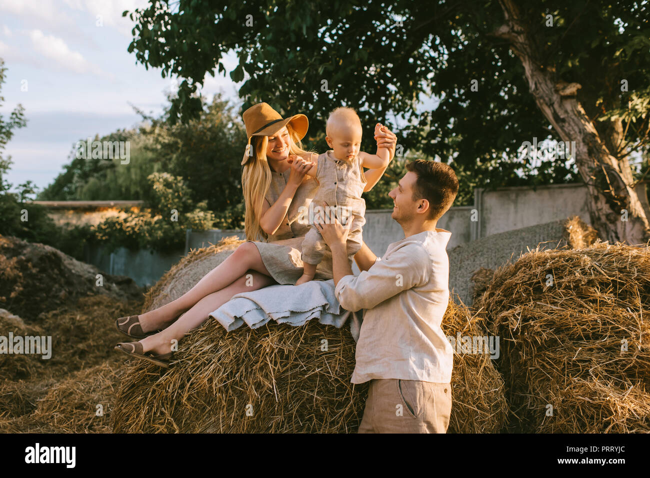 Famille avec peu de fils de lin, les vêtements posés sur le foin à campagne Banque D'Images