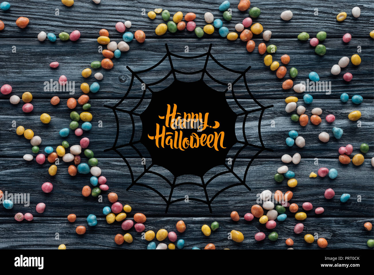 De délicieux bonbons colorés sur fond de bois avec Spider web et 'happy Halloween lettrage' Banque D'Images