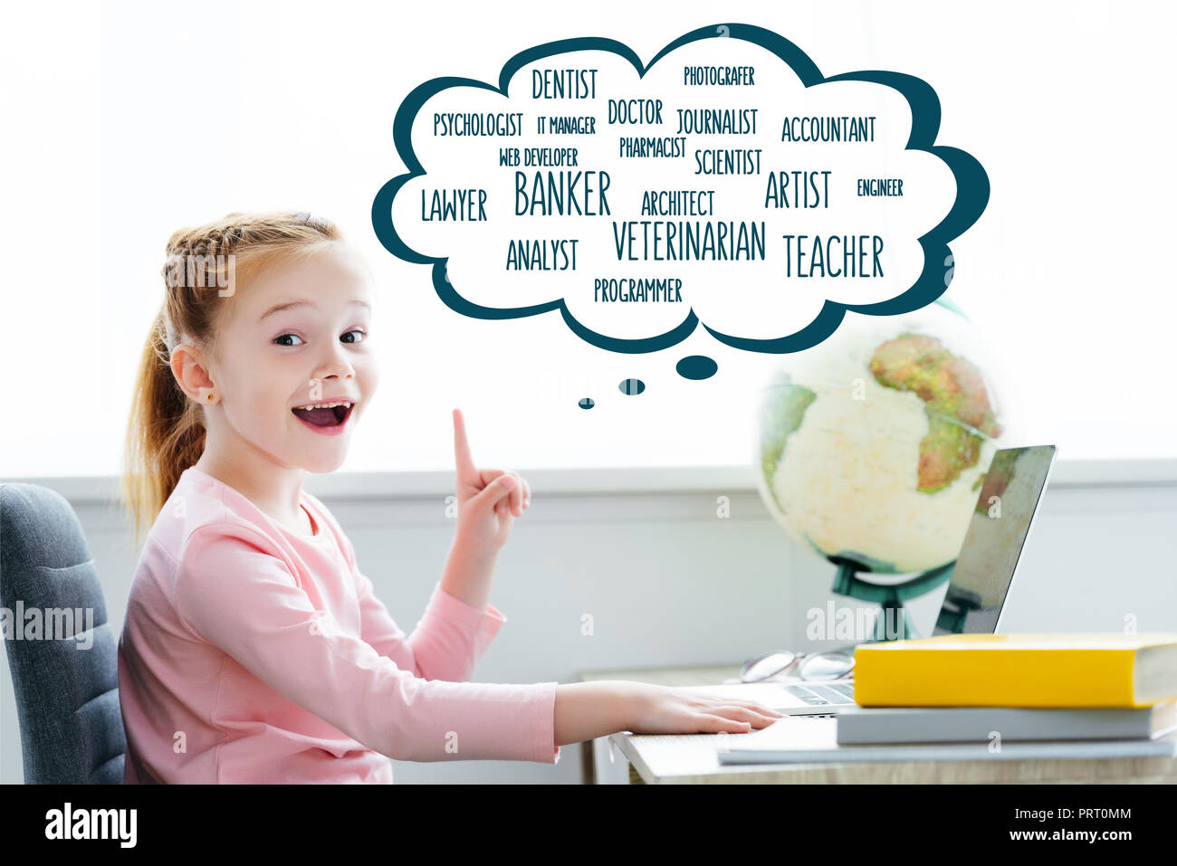 Cheerful redhead enfant qui étudie avec des livres et d'ordinateurs portables et pointant vers le haut sur les mots de différentes professions en bulle Banque D'Images