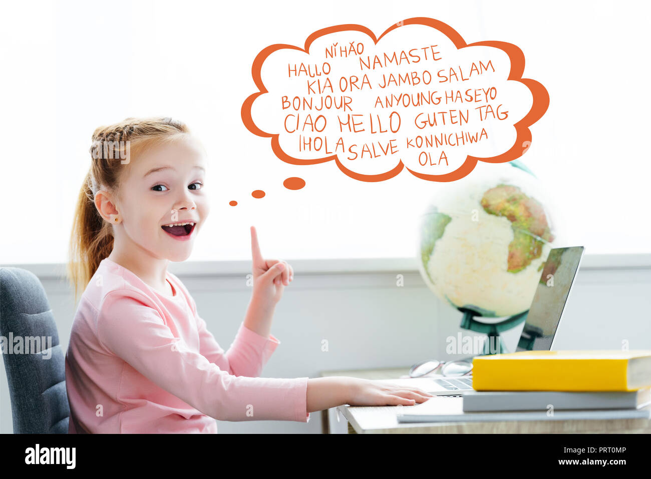 Écolier rousse étudie avec livres et ordinateur portable et pointant vers le haut sur les mots de différentes langues dans bulle Banque D'Images