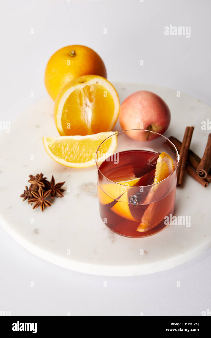Vue en gros de verre de vin chaud, d'épices, Orange et Apple sur table blanc Banque D'Images