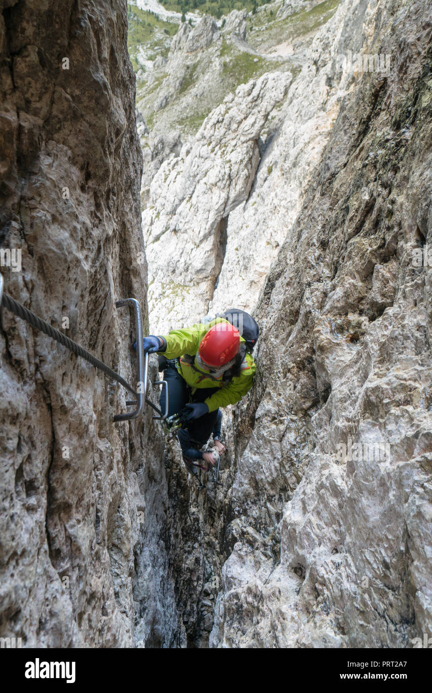 Deux jeunes femmes d'alpinistes passer par une étroite fissure sur une montée raide dans les Dolomites d'Alta Badia en Italie du nord Banque D'Images
