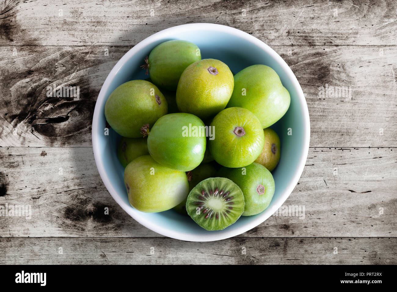 Hardy kiwi fruits ou baies de kiwi sur table Bol en céramique Banque D'Images