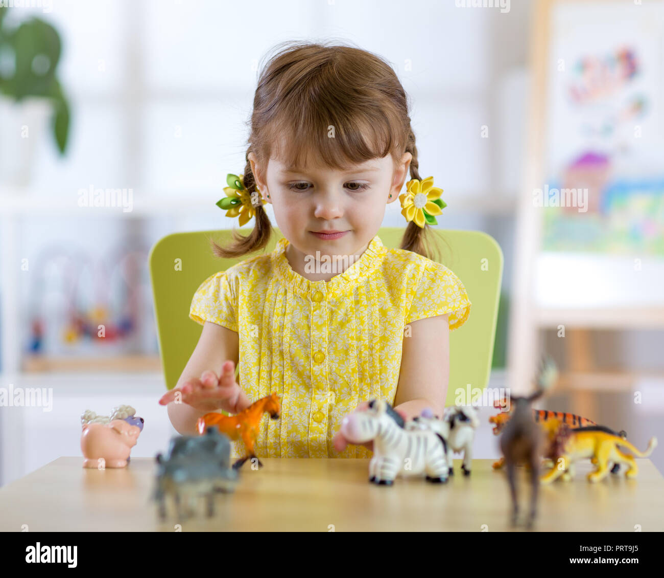 Petite fille joue avec peu d'animaux tout en étant assis à table Banque D'Images