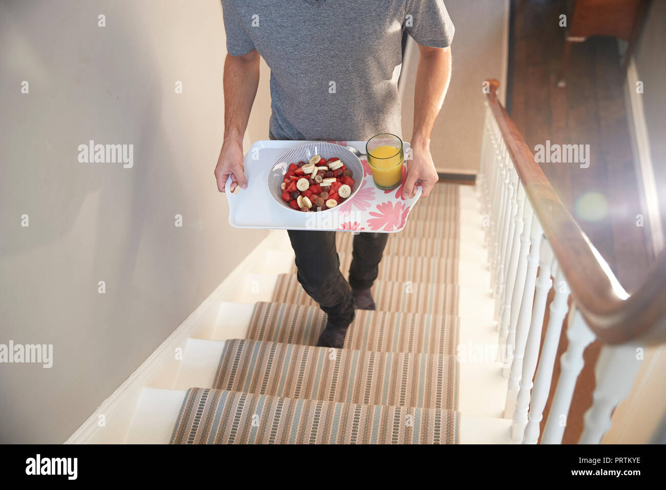 Jeune homme exerçant son plateau de petit-déjeuner à l'étage, du cou vers le bas Banque D'Images Jeune homme exerçant son plateau de petit-déjeuner à l'étage, du cou vers le bas Banque D'Images