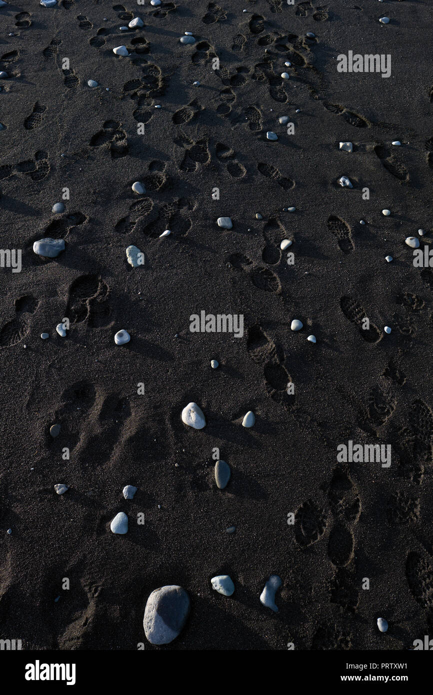 Empreintes laissées par les touristes sur la plage de lave de basalte noir de Jokulsarlon en Islande. Banque D'Images