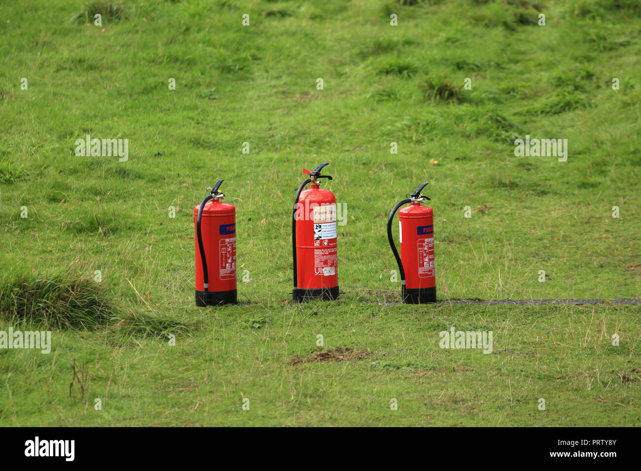 Trois extincteurs debout sur l'herbe. Banque D'Images