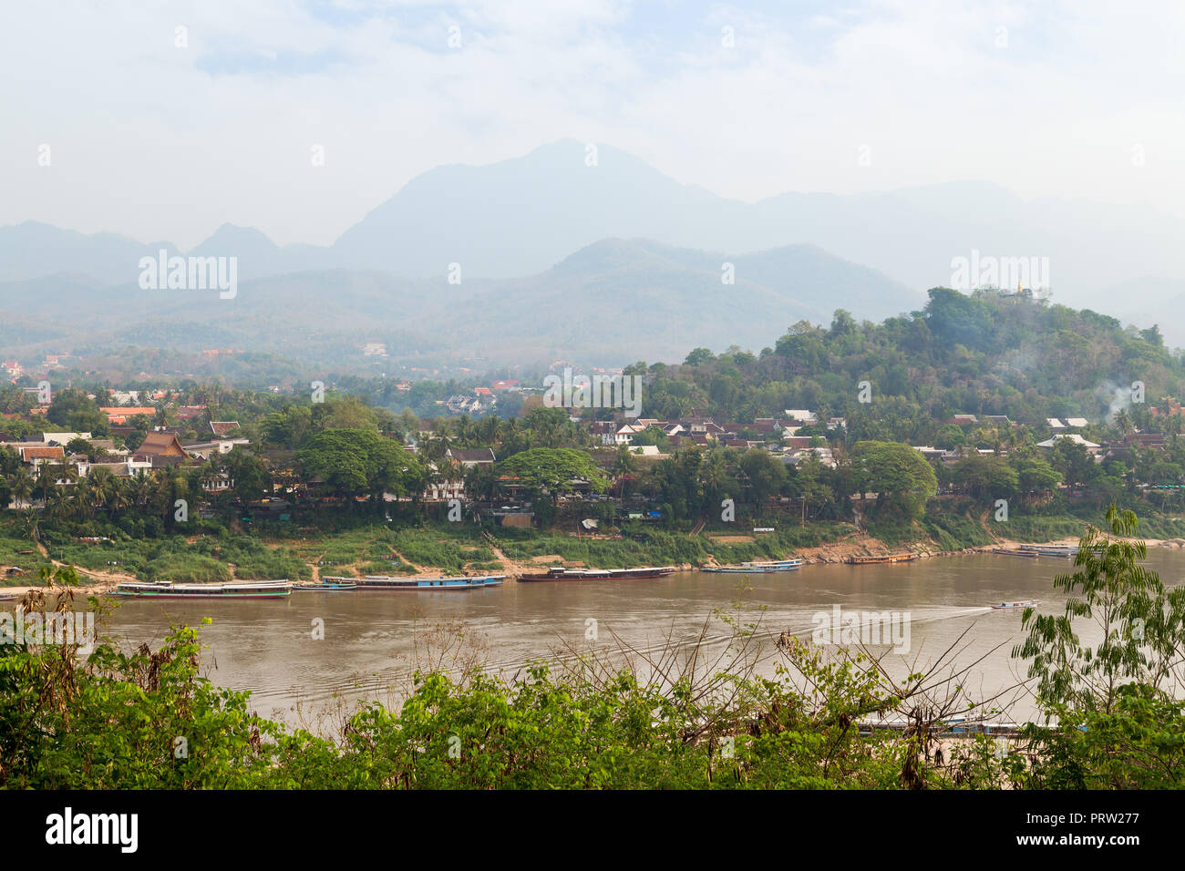 Bateaux amarrés sur le fleuve Mékong, ville de Luang Prabang, le Mont Phousi (Phou Si, Phusi, Phu Si) et les montagnes en arrière-plan à Luang Prabang, Laos. Banque D'Images