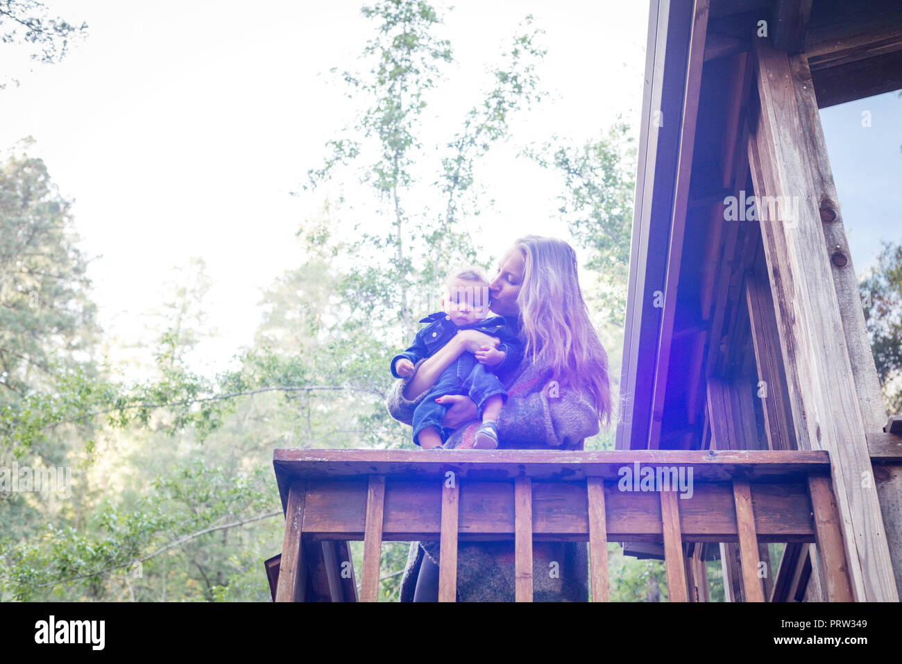 Mère avec bébé sur son balcon de maison en bois en forêt, Cazadero, California, USA Banque D'Images