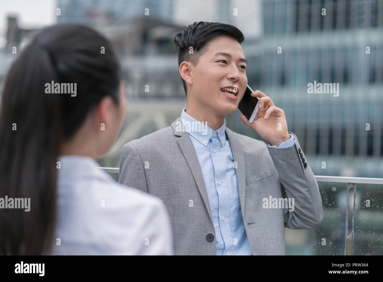 Young businesswoman et man talking on smartphone in ville, Shanghai, Chine Banque D'Images