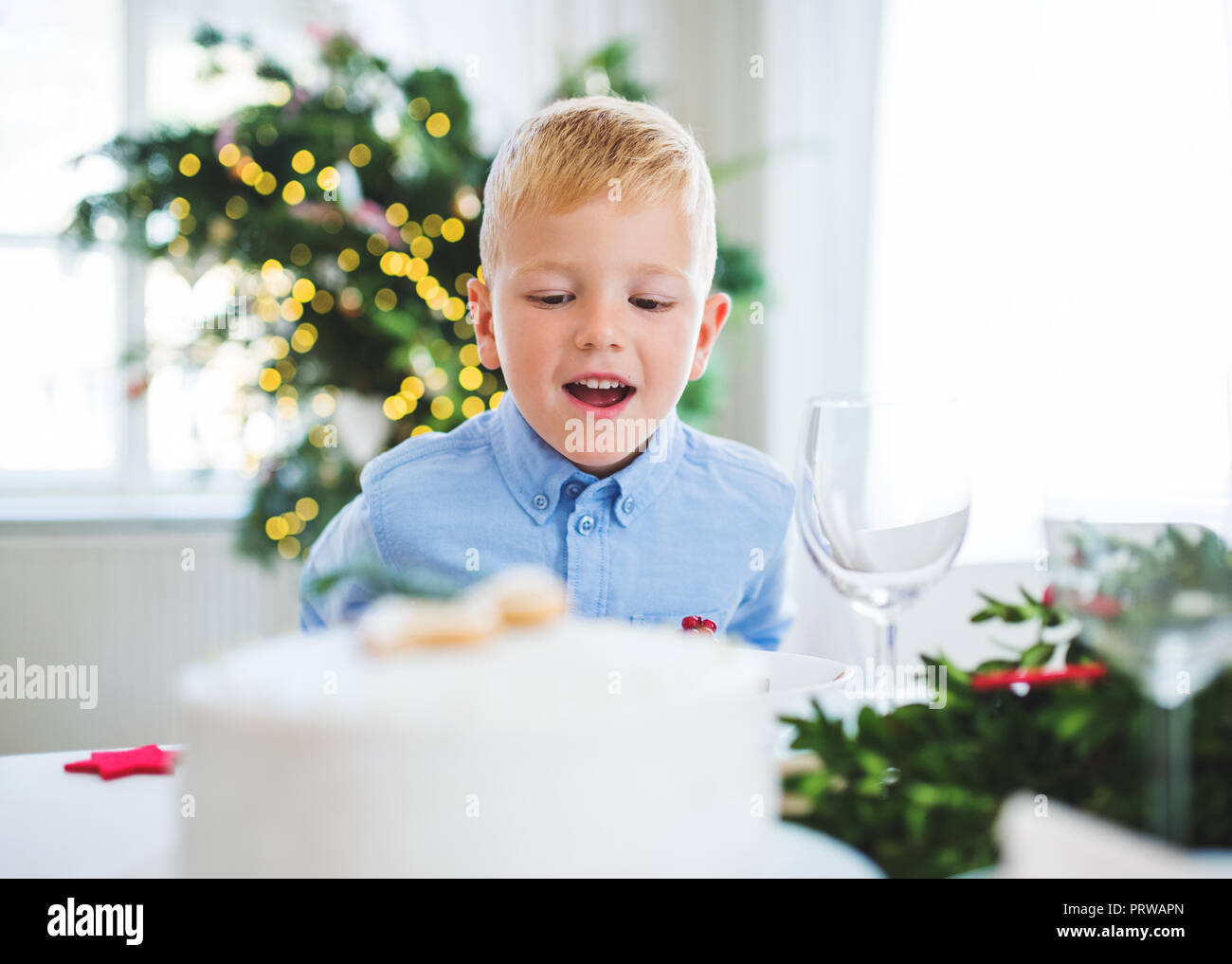 Un petit garçon à la recherche à un gâteau à la maison au moment de Noël. Banque D'Images