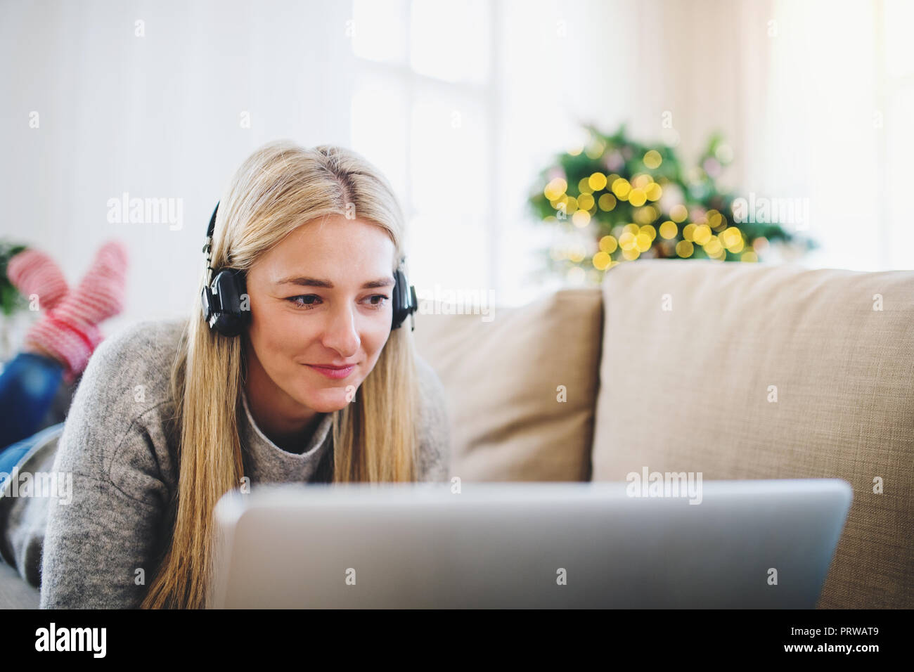 Une jeune femme avec un casque et ordinateur portable à la maison au moment de Noël. Banque D'Images