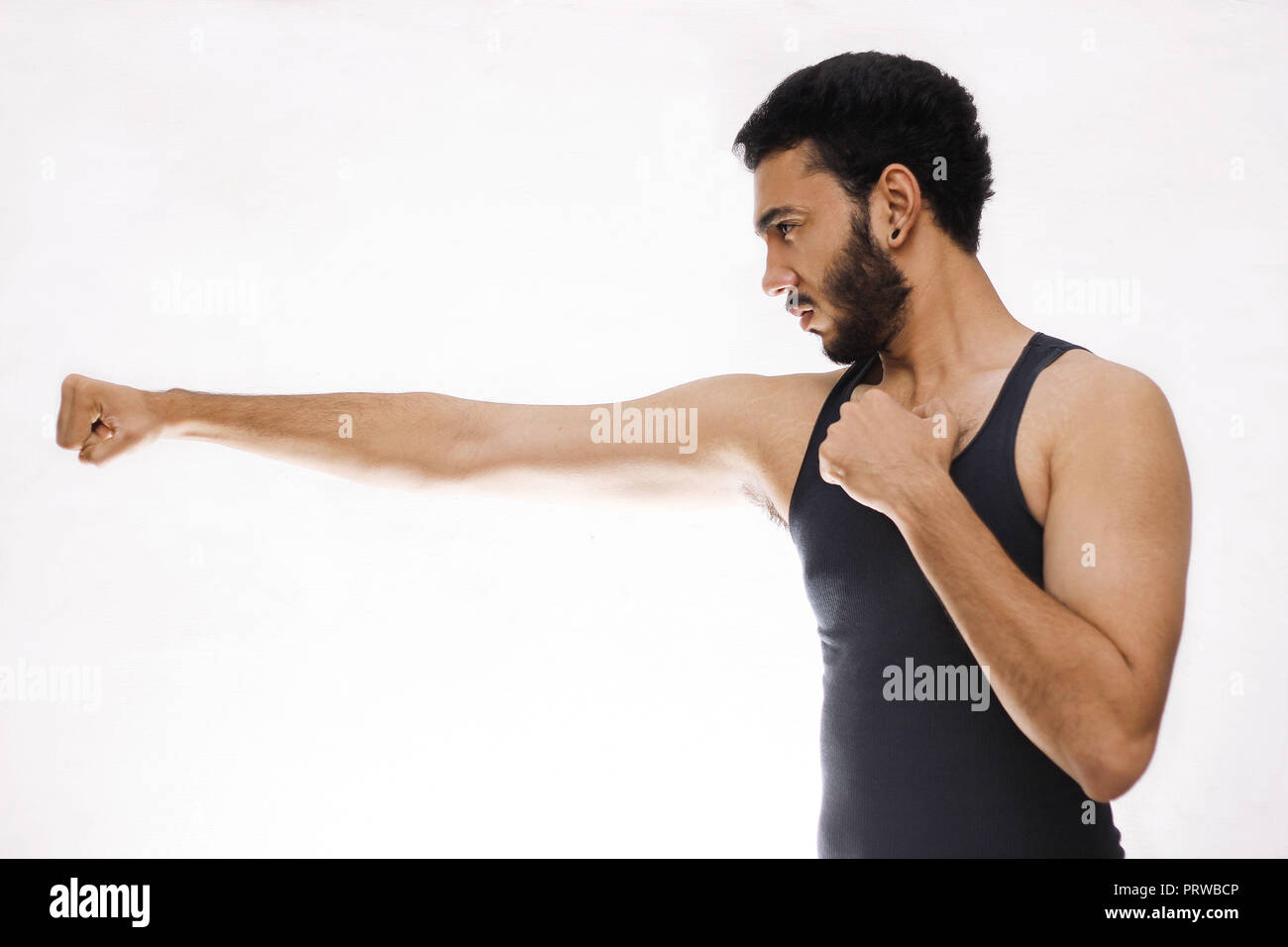 Jeune homme confiant de remise en forme avec des mains très fortes et ses poings fermés isolé sur fond blanc Banque D'Images