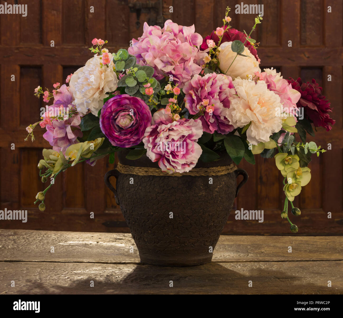 Arrangement de fleurs dans vase vieux sur table en détresse. Banque D'Images