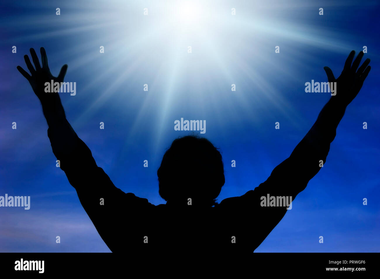 L'homme silhouette aux bras ouverts en face d'une divine lumière dans le ciel Banque D'Images