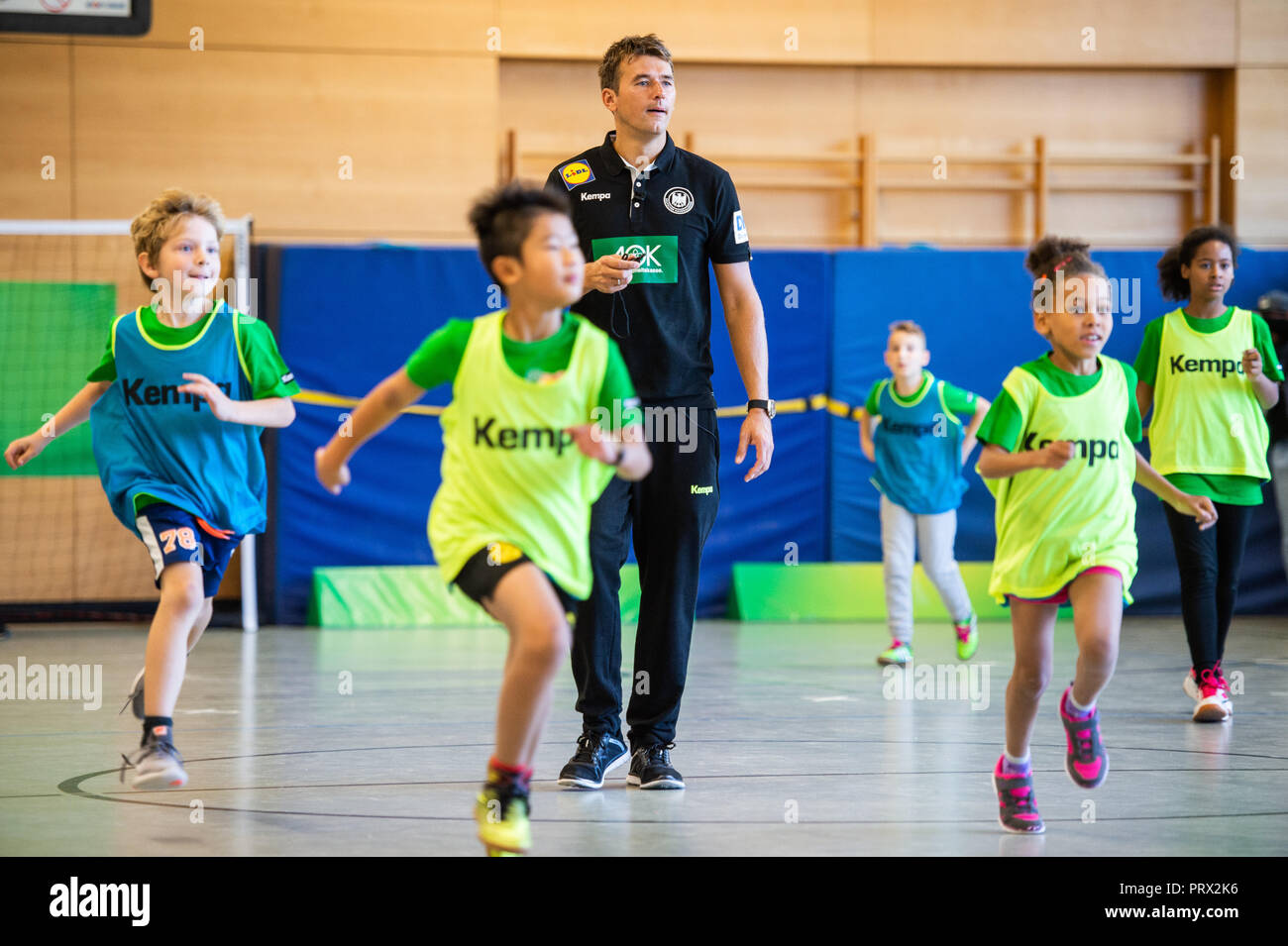 05 octobre 2018, Berlin : Christian Prokop (M), entraîneur de handball nationale, mène un programme de formation avec des élèves de l'école primaire Am Faulen Voir. L'école primaire de Berlin avait gagné un cours de formation de handball avec l'entraîneur national Prokop dans un projet d'école nationale de la Fédération allemande de Handball (DHB) et l'AOK. Avec ce projet, les deux partenaires veulent motiver les enfants pour plus d'exercice et de handball. Photo : Arne Immanuel Bänsch/dpa Banque D'Images