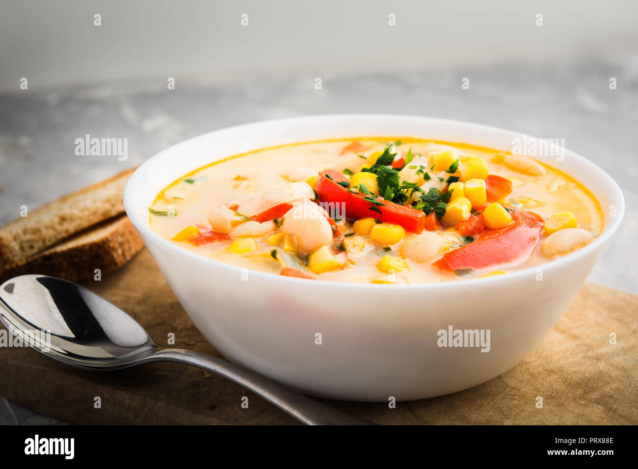 Crème de Succotash dans bol blanc avec des légumes sur planche de bois Banque D'Images