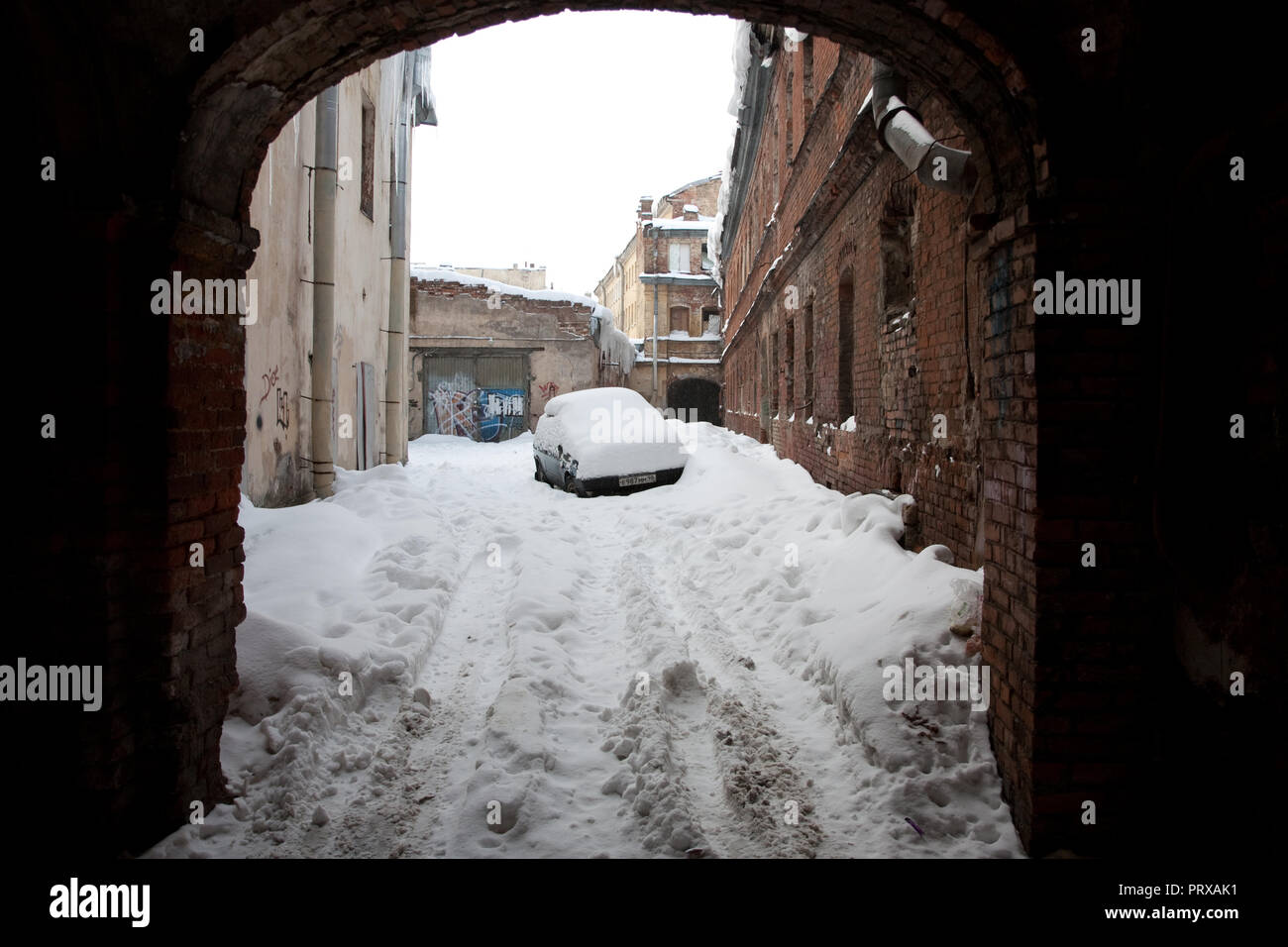 Saint-pétersbourg, Russie ; - le 5 janvier 2011 : d'énormes glaçons pendant d'un toit d'un bâtiment ancien ; voiture abandonnée couvertes de neige Banque D'Images