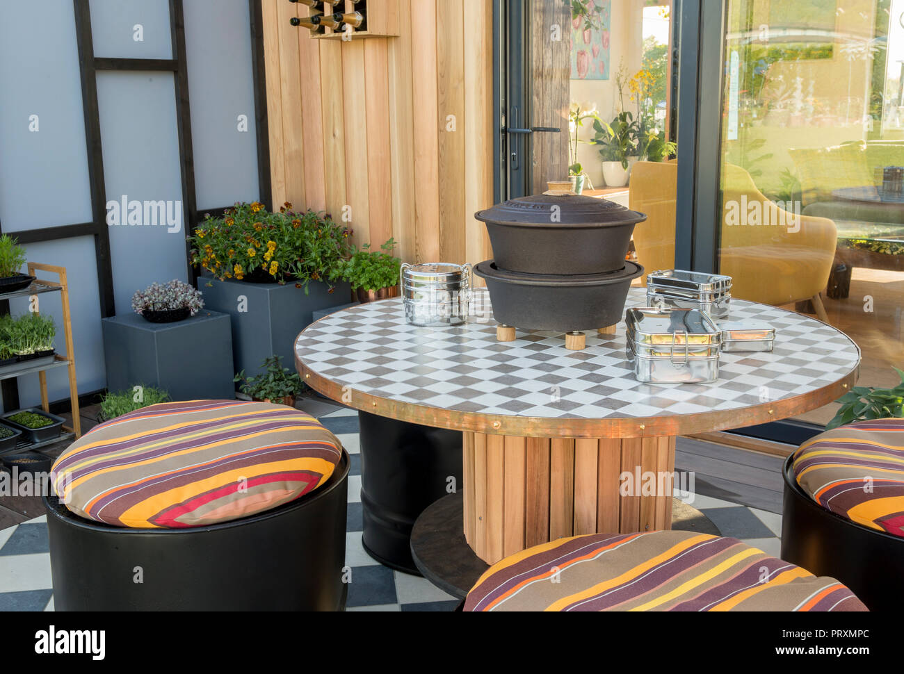 Balcon jardin avec table en bois recyclé, sièges de tambour d'huile de table, coussins, patio extérieur salle à manger, violas, succulents et micro greens UK Banque D'Images
