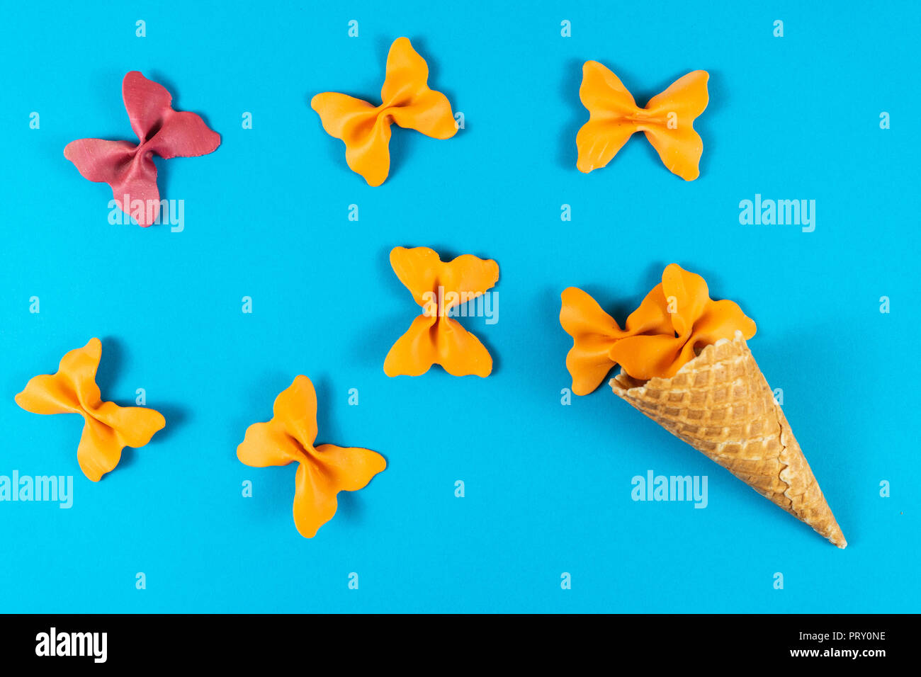 Mise en page d'été créative faite de cornet de crème glacée, cornets et gaufres pâtes de couleur papillon lumineux sur la semoule fond bleu clair. Concept minimal Banque D'Images