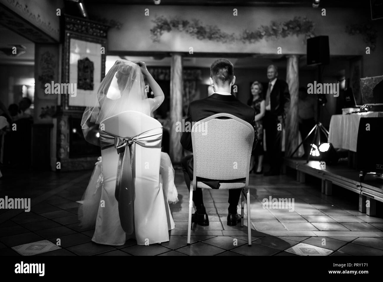 Couple marié au mariage assis sur des chaises en noir et blanc Banque D'Images