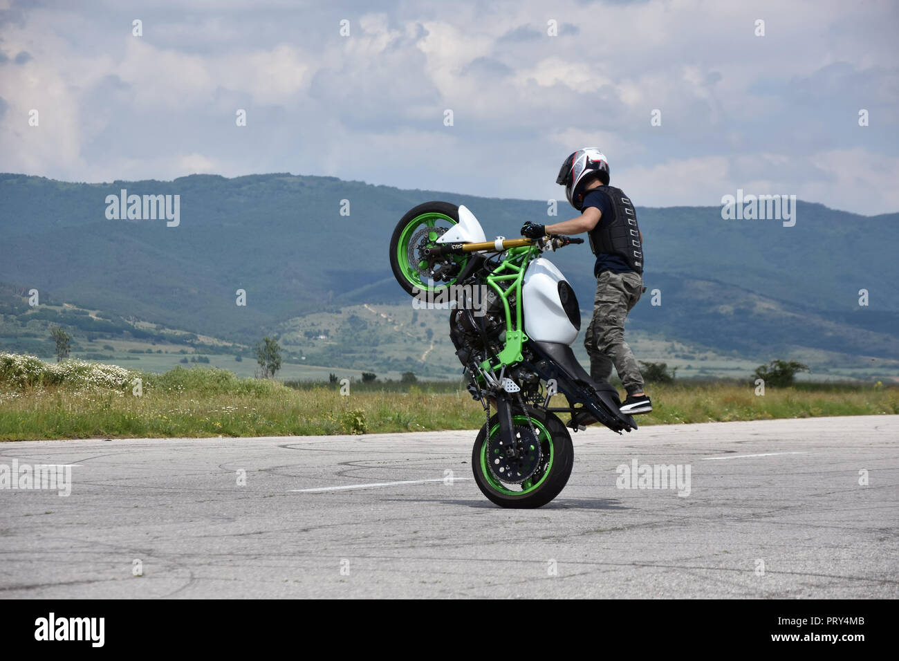 Stunt moto en action. Jeune homme biker freestyle extrême sur l'échelle de formation abandonnés vides airplane Banque D'Images