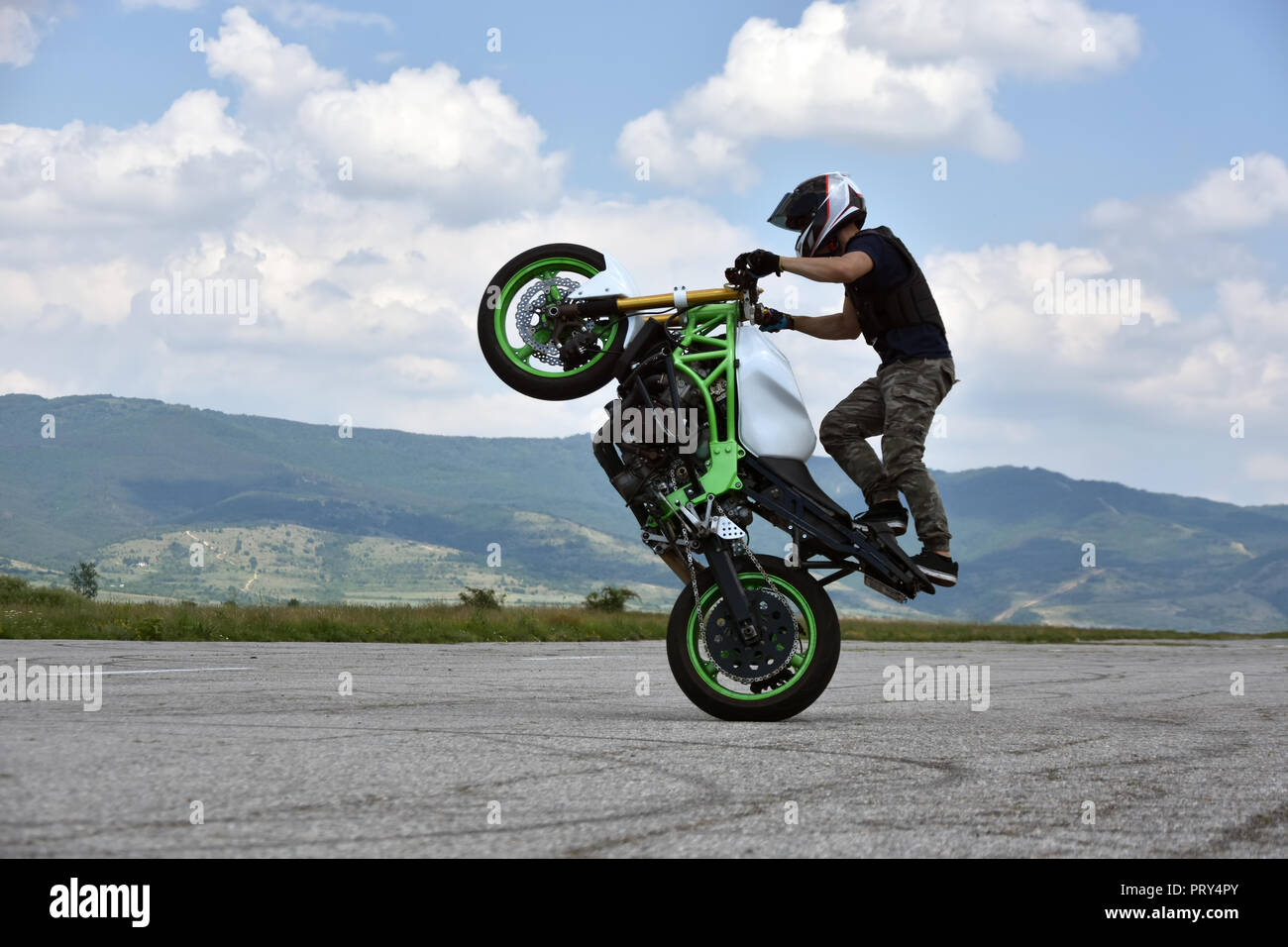 Stunt moto en action. Jeune homme biker freestyle extrême sur l'échelle de formation abandonnés vides airplane Banque D'Images