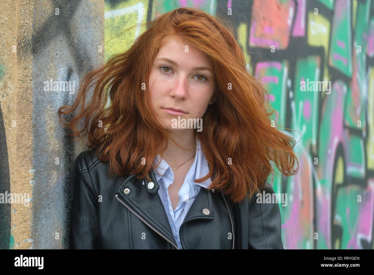 Portrait, fille rousse, jeune femme en blouson de cuir à l'avant du graffiti, à Finale Ligure, Riviera di Ponente, Ligurie Banque D'Images