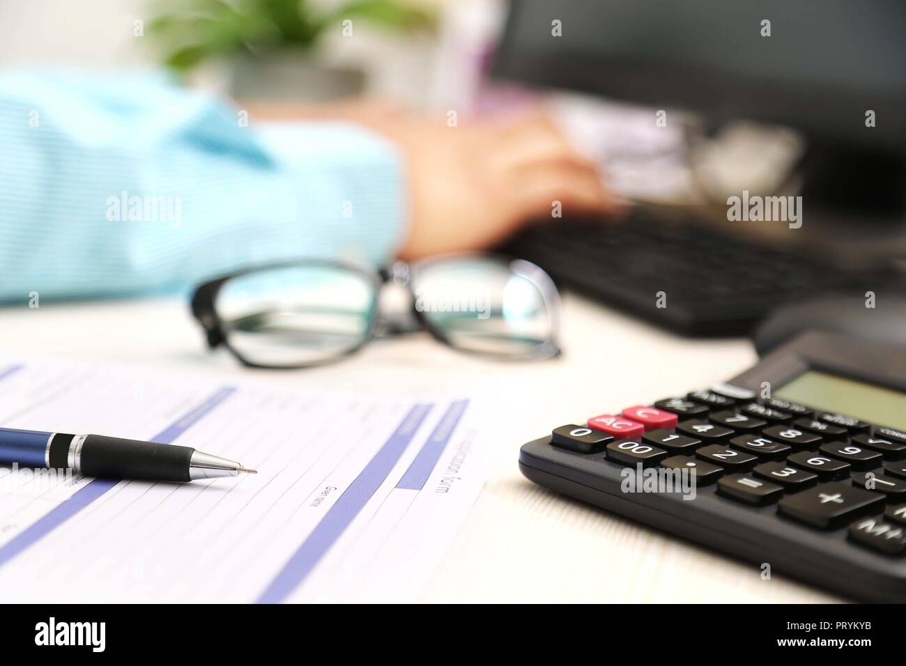 Photo de l'homme main est de taper au clavier. Photo du formulaire de demande, un stylo, calculatrice et lunettes. Banque D'Images