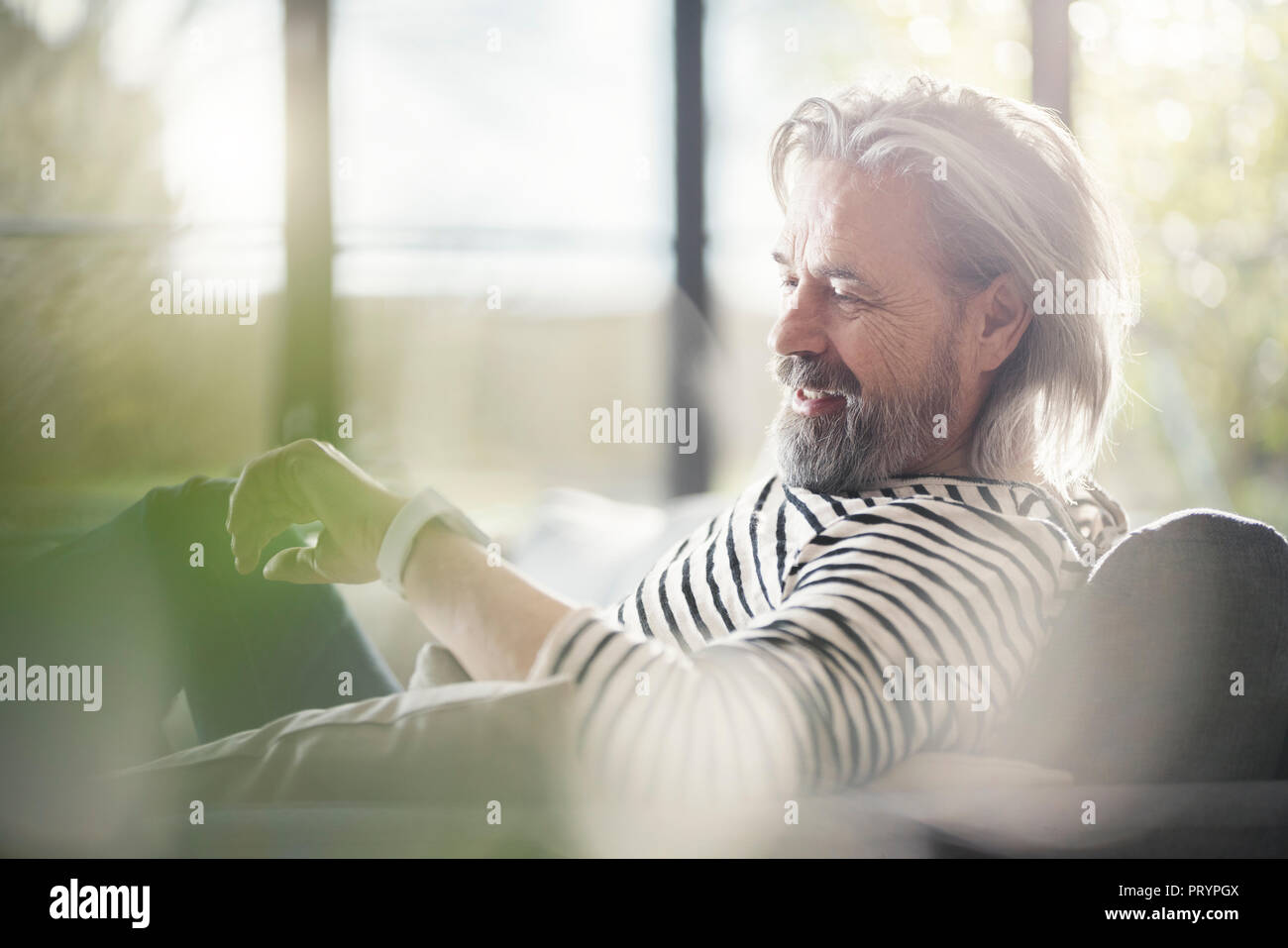 Senior man sitting on couch, parlant dans smartwatch Banque D'Images